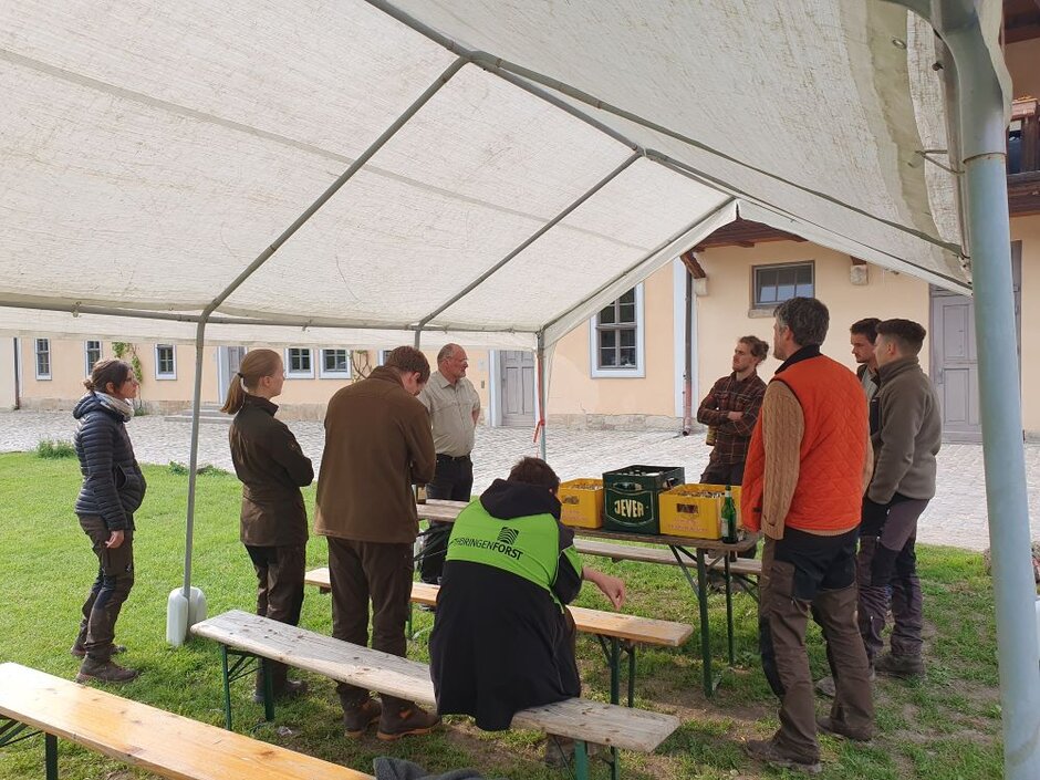 Die Teilnehmer der Exkursion sitzen zusammen mit dem Vorstand von ThüringenForst beim Grillen.